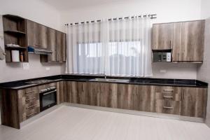 una cocina con armarios de madera y una ventana en T&T Apartment, en Ndola