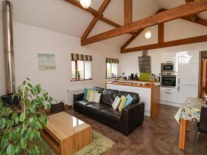 a living room with a leather couch and a kitchen at Dairy Cottage in Staintondale
