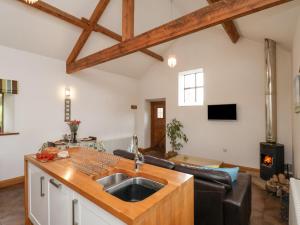 uma cozinha com um lavatório e uma sala de estar com um sofá em Dairy Cottage em Staintondale