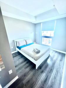 um quarto com uma cama branca e pisos em madeira em Cozy Condo Near EatonCentre Mall em Toronto