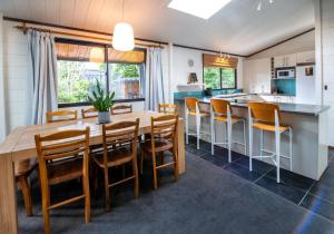 羅托魯阿的住宿－Aura @ Home，厨房以及带木桌和椅子的用餐室。