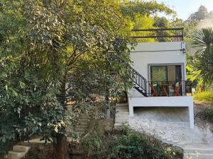 a white house with a window and a bench at Lamtam Maesa Resort ลำธารแม่สา รีสอร์ท in Mae Rim