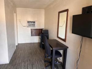 een kleine kamer met een bureau en een televisie bij Border Motel in Calexico