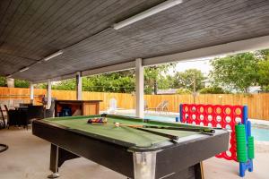 Home with pool and games in central San Antonio في سان انطونيو: طاولة بلياردو جالسة تحت مظلة بجوار حمام السباحة