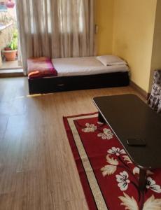 Zimmer mit einem Bett, einem Tisch und einem Teppich in der Unterkunft Apartment Rupas in Kathmandu