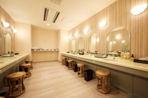 uma sala de vestir com uma fila de lavatórios e bancos em HOTEL FUKURACIA OSAKA-BAY em Osaka