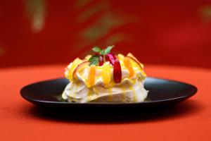 a piece of cake on a black plate on a red table at Sunset INN by Pro-Ema in Dili