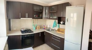 uma cozinha com armários castanhos e um frigorífico branco em Elegant 3-room apartment near iMall: Kievskaja Street em Bishkek