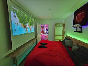 ein Schlafzimmer mit einem großen roten Bett mit einem großen Bildschirm in der Unterkunft L'Appart Spa, Jacuzzi & Sauna in Differdingen