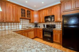 a kitchen with wooden cabinets and a black refrigerator at Modern Townhome,boston Vacation,2 Bath,pkg,deck in Brookline