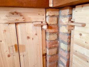 a room with wooden walls and a brick wall at Nature Lodge Csesztve in Csesztve
