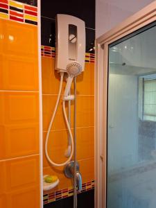 eine Dusche im Bad mit orangefarbener Wand in der Unterkunft The Hug Condo Bangsaen in Bangsaen