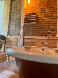 Cette chambre dispose d'une baignoire et d'un mur en briques. dans l'établissement Nature Lodge Csesztve, à Csesztve