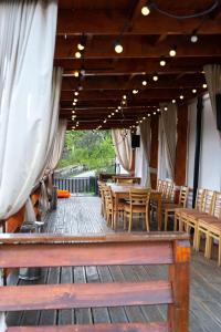 a patio with wooden chairs and tables and curtains at Pensiunea Club Dioda in Curtea de Argeş