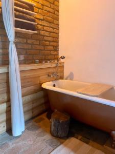 a bath tub in a bathroom with a brick wall at Nature Lodge Csesztve in Csesztve