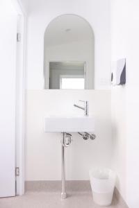 Baño blanco con lavabo y espejo en Somewhere To Stay Backpackers, en Brisbane