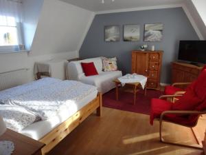 a bedroom with a bed and a couch and a tv at Feldhörn Comfortable holiday residence in Zetel