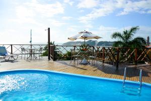 einen Pool mit einem Sonnenschirm und einem Tisch in der Unterkunft Marsallis Praia Hotel in Natal