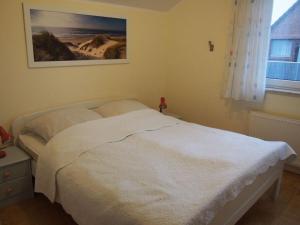 um quarto com uma cama branca e uma fotografia na parede em Deichwiege Modern retreat em Horumersiel