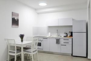 uma cozinha branca com uma mesa e cadeiras e um frigorífico em Suite Apartment #61 By Hashdera Eilat em Eilat