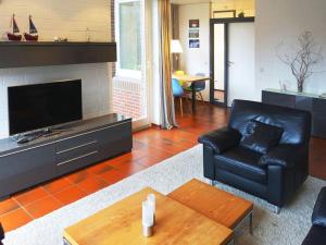 a living room with a black leather couch and a television at Christel Modern retreat in Langeoog