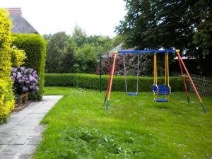 einen Hof mit einer Schaukel im Gras in der Unterkunft North Sea dike Modern retreat in Sehestedt + 6 Fotos