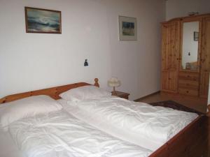 um quarto com uma grande cama branca com uma estrutura em madeira em Strandnelke Modern retreat em Sehestedt