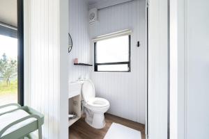 a white bathroom with a toilet and a window at Forest View Cottage 1 in Jiaoxi