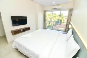 um quarto com uma cama e uma televisão de ecrã plano em Swarnam Hotel em Old Goa