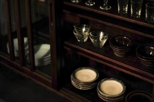 a shelf filled with plates and bowls and glasses at SOUQ Renovated Townhouse in Himeji Quiet Market District in Himeji