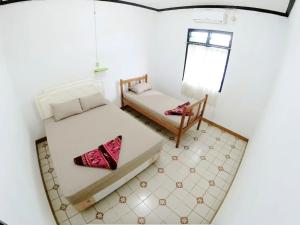 Cette chambre dispose de deux lits, d'une chaise et d'une fenêtre. dans l'établissement Guest House MW 46 by NmRooms, à Demangan
