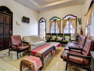 - un salon avec des meubles en cuir et des fenêtres dans l'établissement Guest House MW 46 by NmRooms, à Demangan