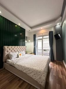 1 dormitorio con 1 cama grande y pared verde en Homestay Tháng 5, en Da Lat