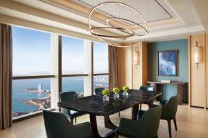 a dining room with a table and chairs and a chandelier at The St. Regis Qingdao in Qingdao