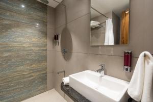 uma casa de banho com um lavatório e um chuveiro em The Living Hub Hotel, Kolhapur- Walkable From Central Bus Station em Colhapur
