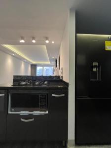 a kitchen with a black stove and a refrigerator at Kevin Apartamento Moderno en Cali in Cali