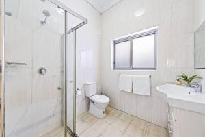 een witte badkamer met een toilet en een wastafel bij Cozy 4 Bedroom House at Prime Location in Sydney