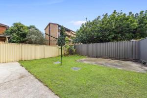 een tuin met een hek en een paal in het gras bij Cozy 4 Bedroom House at Prime Location in Sydney