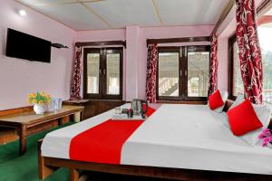 una camera da letto con un letto grande con cuscini rossi di Hotel O Hema Holiday Home a Manāli