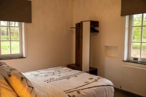 Un dormitorio con una cama y dos ventanas en Tussen Heide en Bos vlakbij Sentower Park, en Opglabbeek 24 fotos más