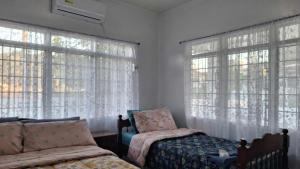 1 dormitorio con 2 camas y ventanas grandes en Condons Beach House, en Caba
