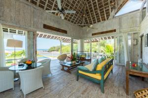 a living room with a lot of furniture and windows at Villa Sungai Laut in Canggu