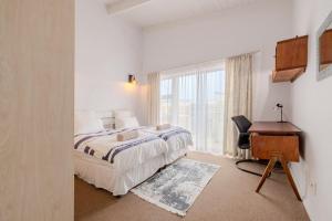 um quarto com uma cama, uma secretária e uma janela em The Waterfront Cottage F3 em Swakopmund