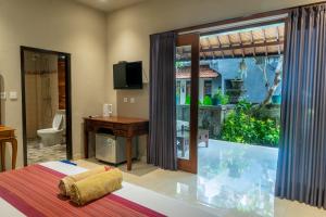 a room with a bedroom with a tub and a window at Warsa's Garden Bungalow and Spa in Ubud