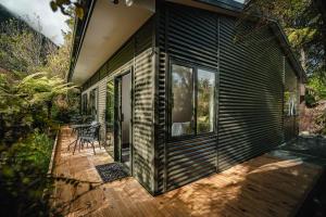 una terrazza in legno con una sedia su una casa di Forest View Franz Josef a Franz Josef