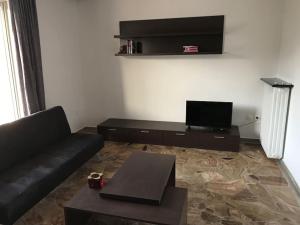 uma sala de estar com um sofá preto e uma televisão de ecrã plano em Sunrise View Apartment em Quios