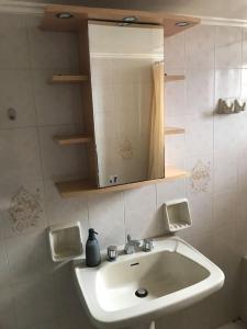 La salle de bains est pourvue d'un lavabo blanc et d'un miroir. dans l'établissement Sunrise View Apartment, à Chios