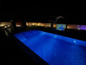 una piscina por la noche con TV en el fondo en Chaitali The Villa, en Santiniketan