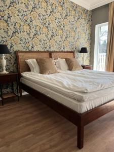 a bed in a bedroom with floral wallpaper at Hotell Toftalund in Halmstad