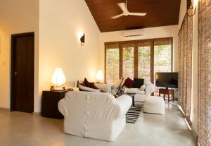 a living room with white furniture and a ceiling fan at Turtle Pond Wilpattu in Wilpattu